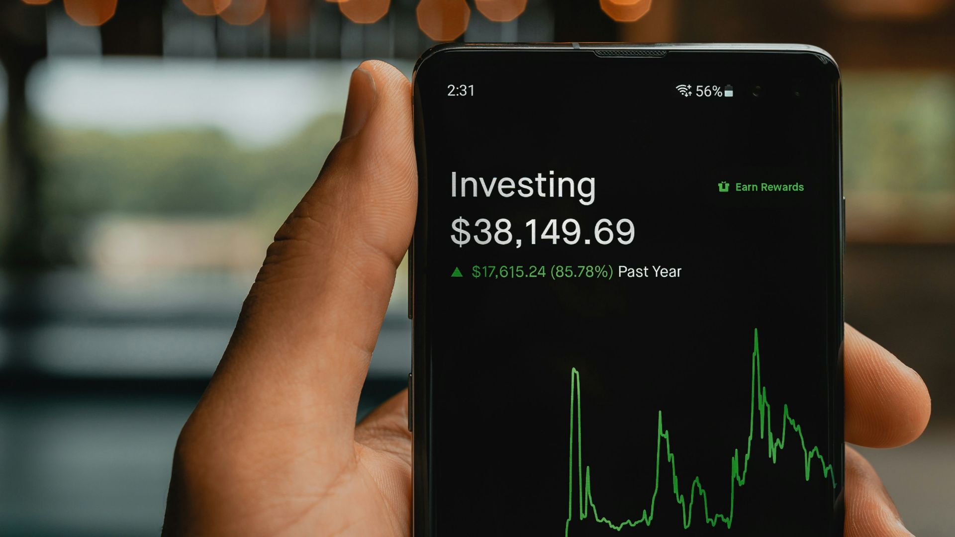 a person holding up a cell phone with a stock chart on it