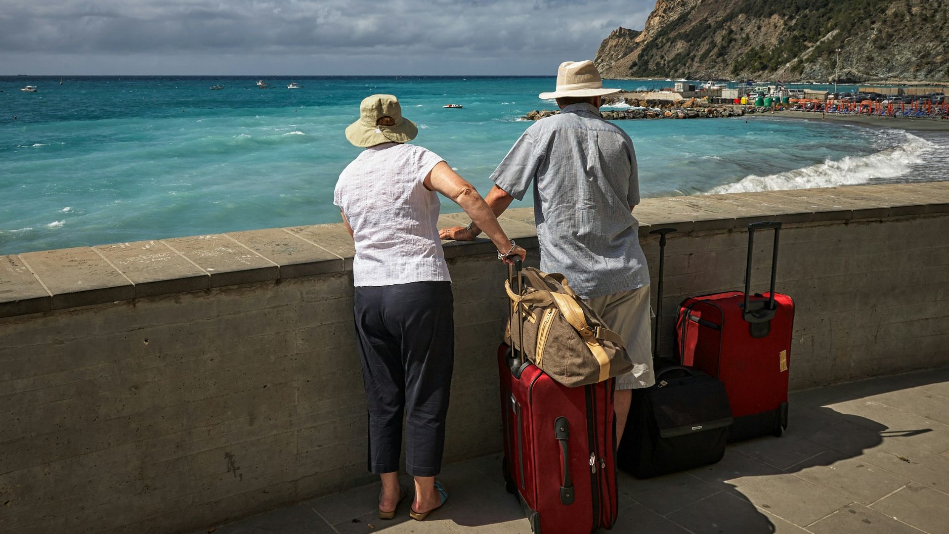 man and woman standing beside concrete seawall looking at beach