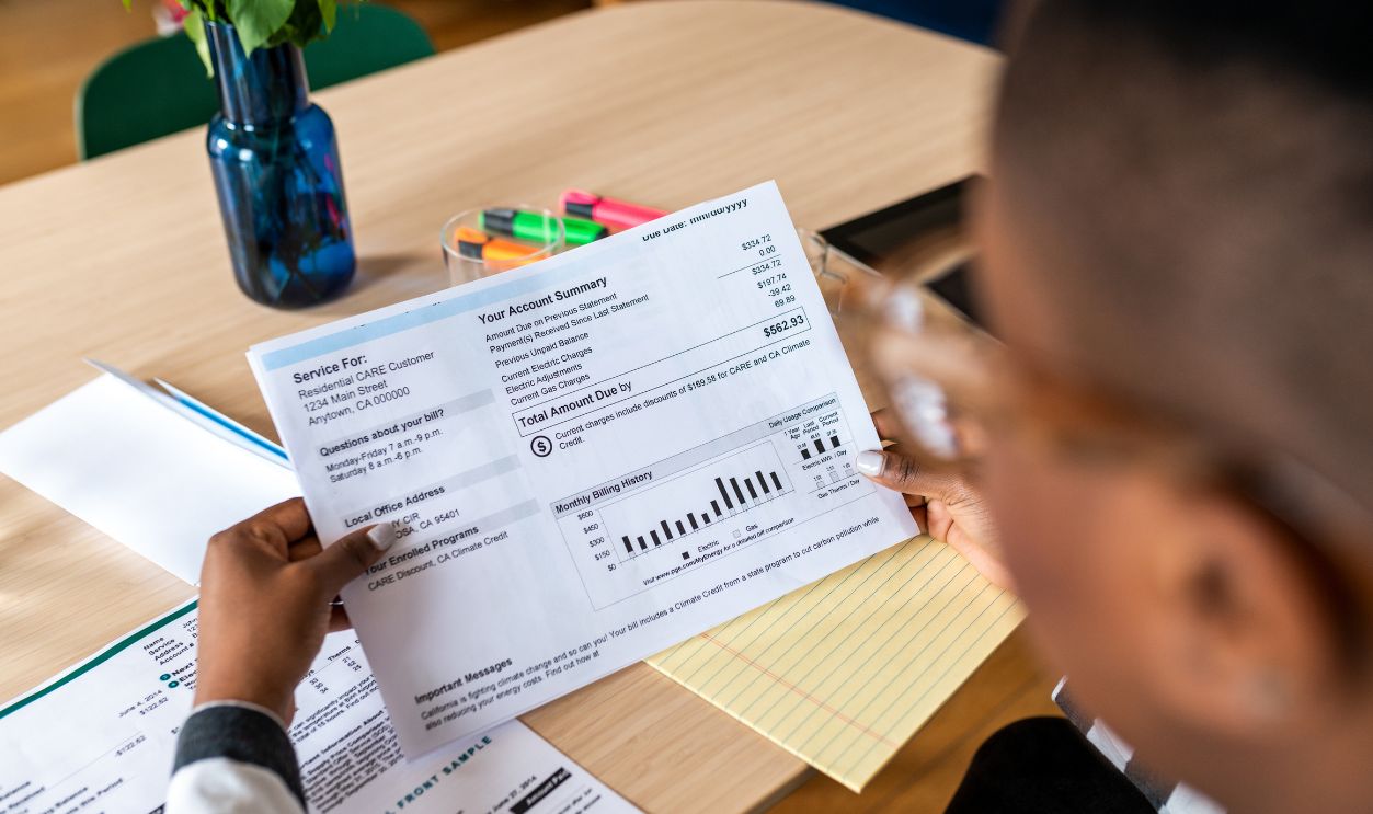 Gettyimages - 1321935762, A young woman looks at the electricity bill - stock photo Over shoulder photo of woman looking at the bill