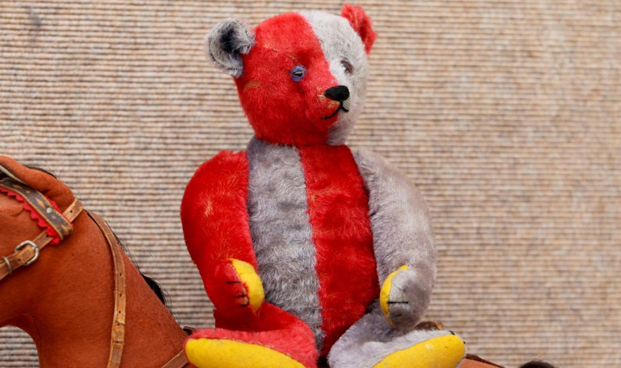 A unique Steiff Harlequin Teddy Bear with red and blue mohair, circa 1925, sits on a Steiff felt ride-on horse during a photocall at Christie's in London, before it goes under the hammer as part of a 1m Teddy Bear and Soft Toy auction on 13 October where the bear is expected to fetch between 50,000 and 80,000.