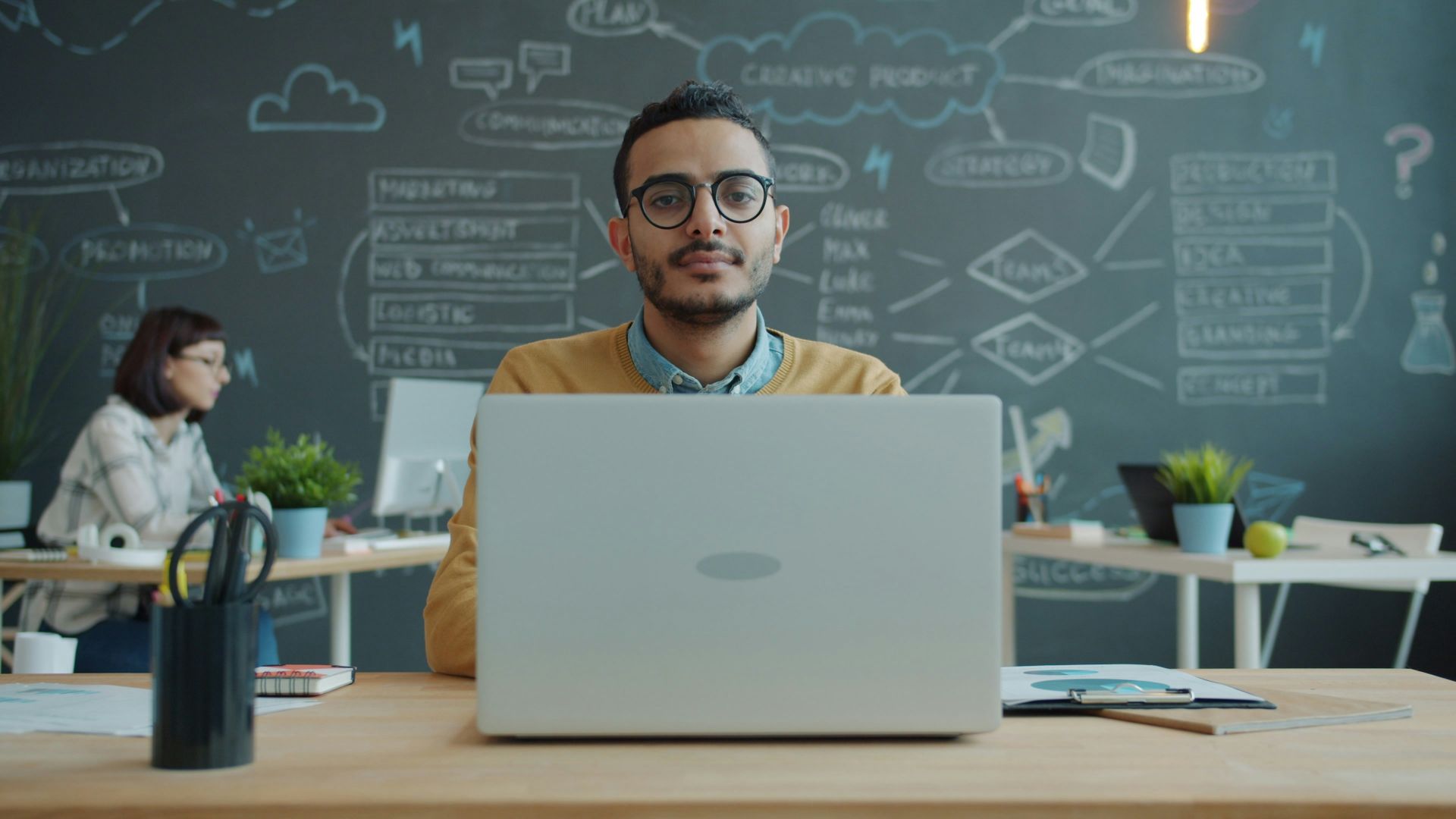 Man wearing glasses works on laptop in office