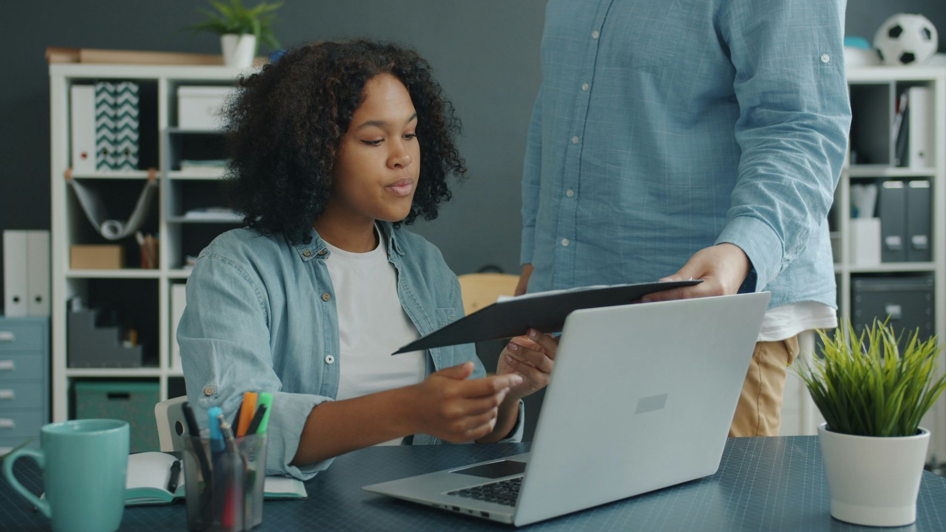 Two colleagues reviewing documents at an office desk.