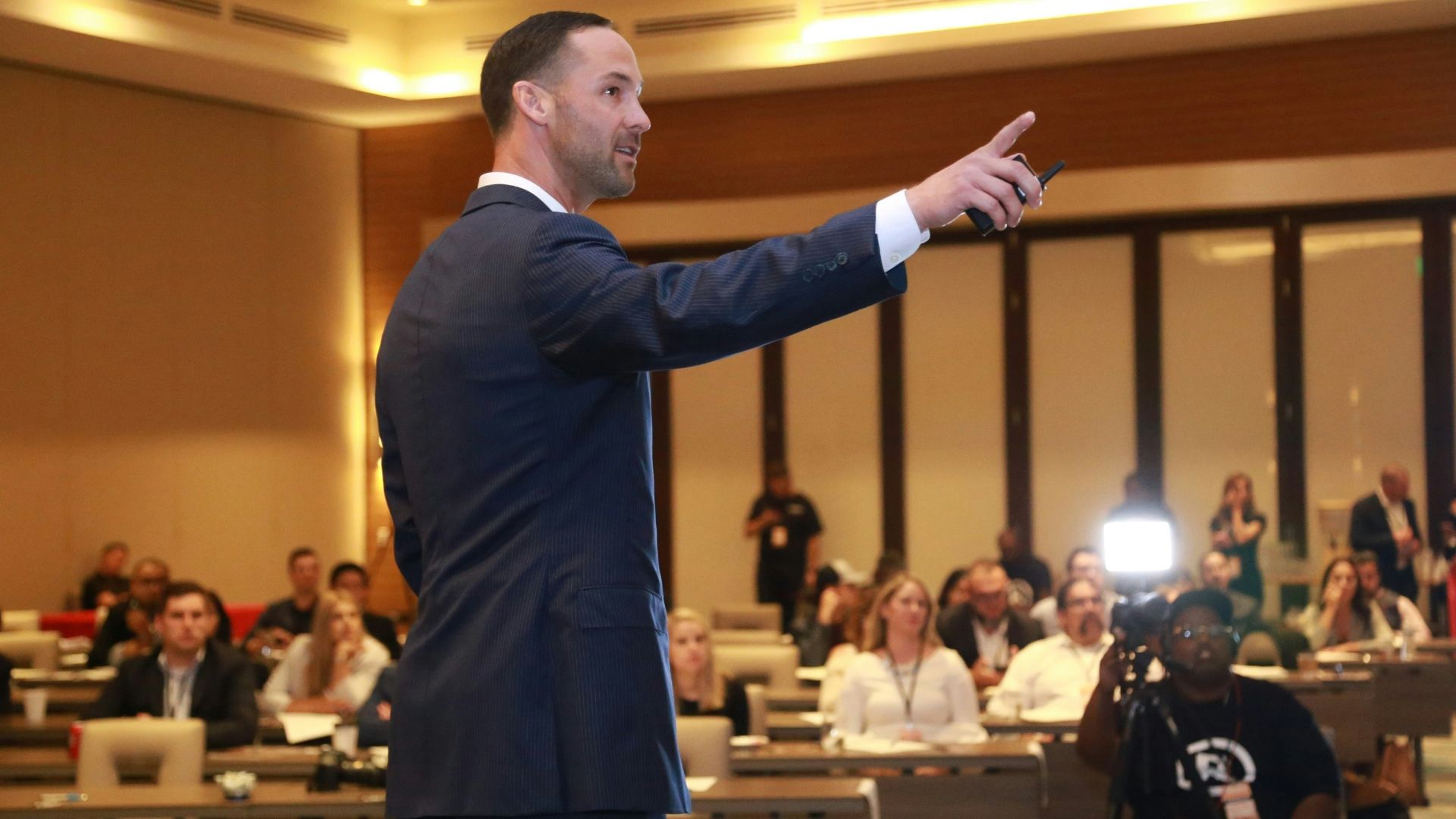 man in black suit standing on stage