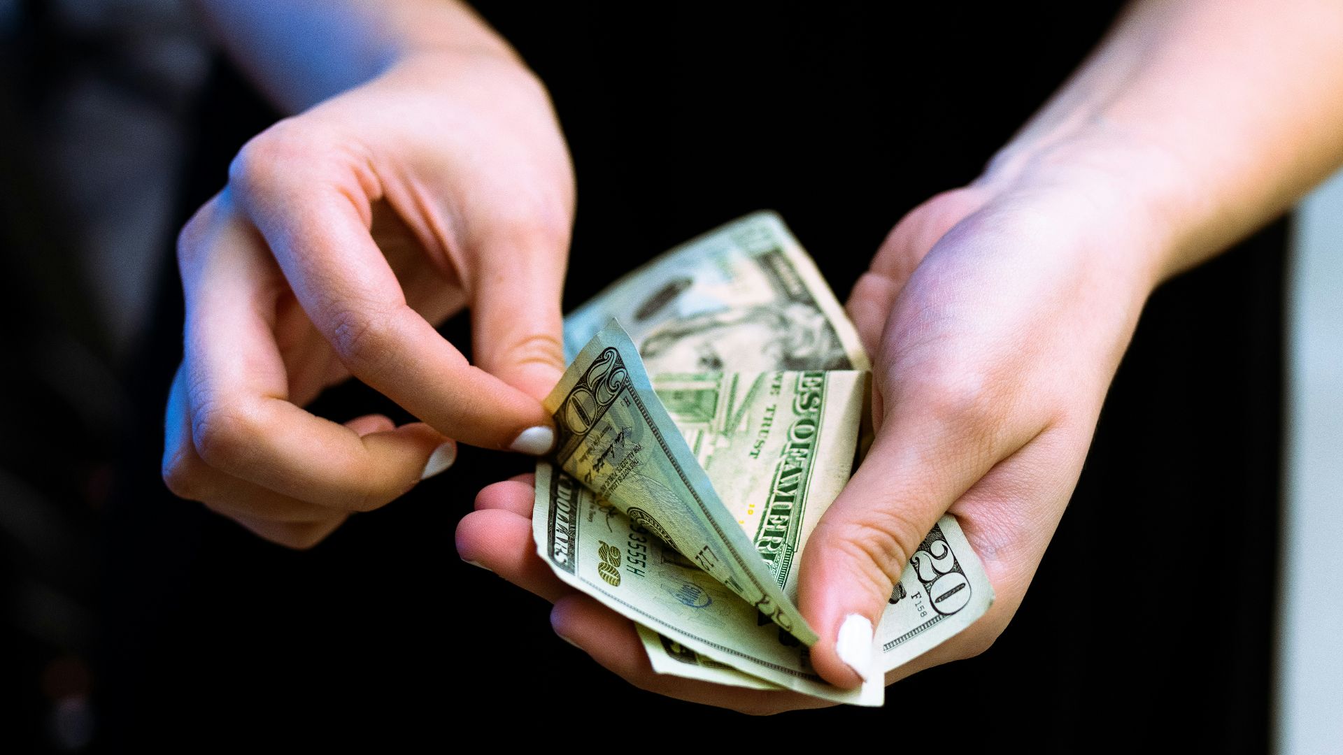 person holding fan of 100 us dollar bill