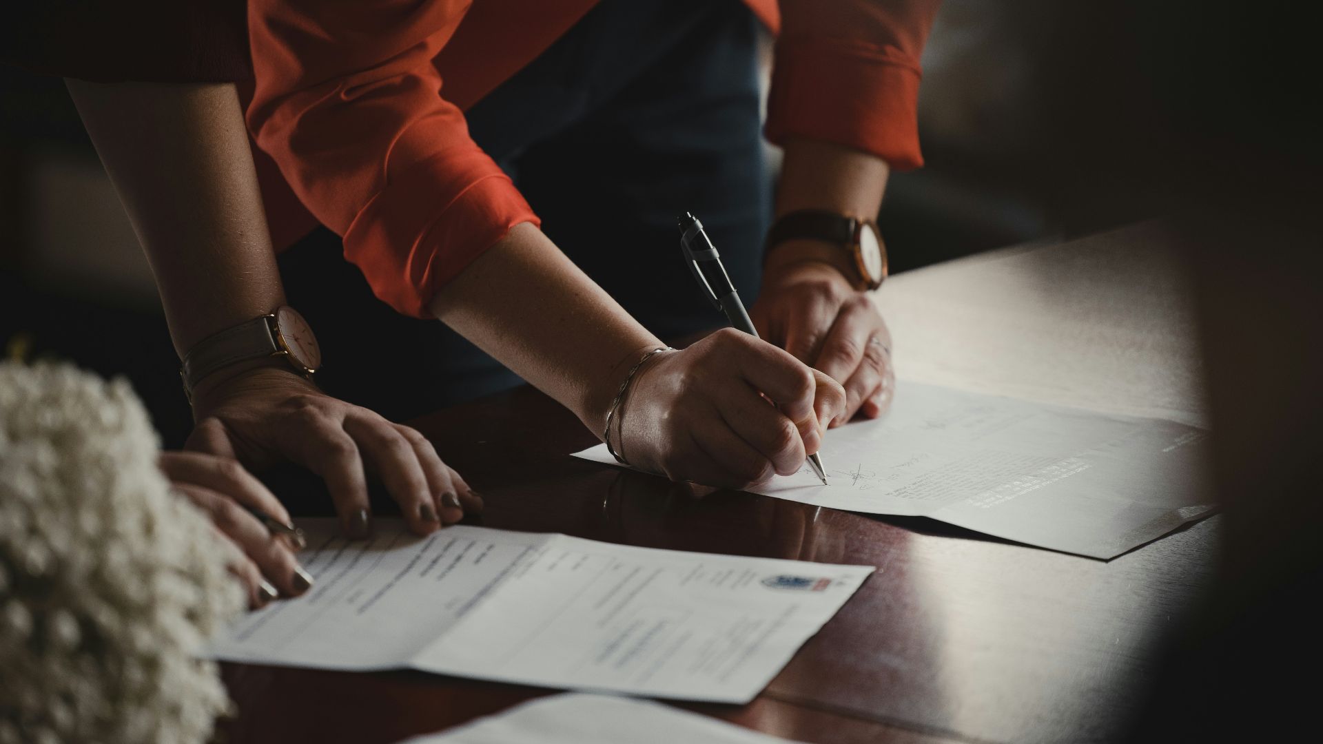 person in orange long sleeve shirt writing on white paper