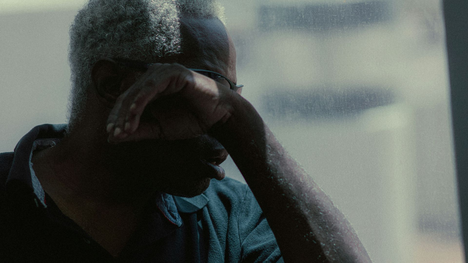 A man with silver hair covers his face.