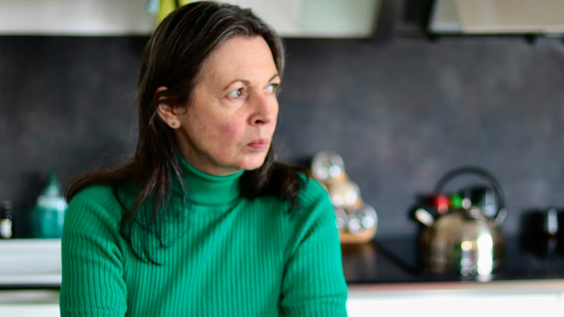 a woman sitting at a table in a kitchen