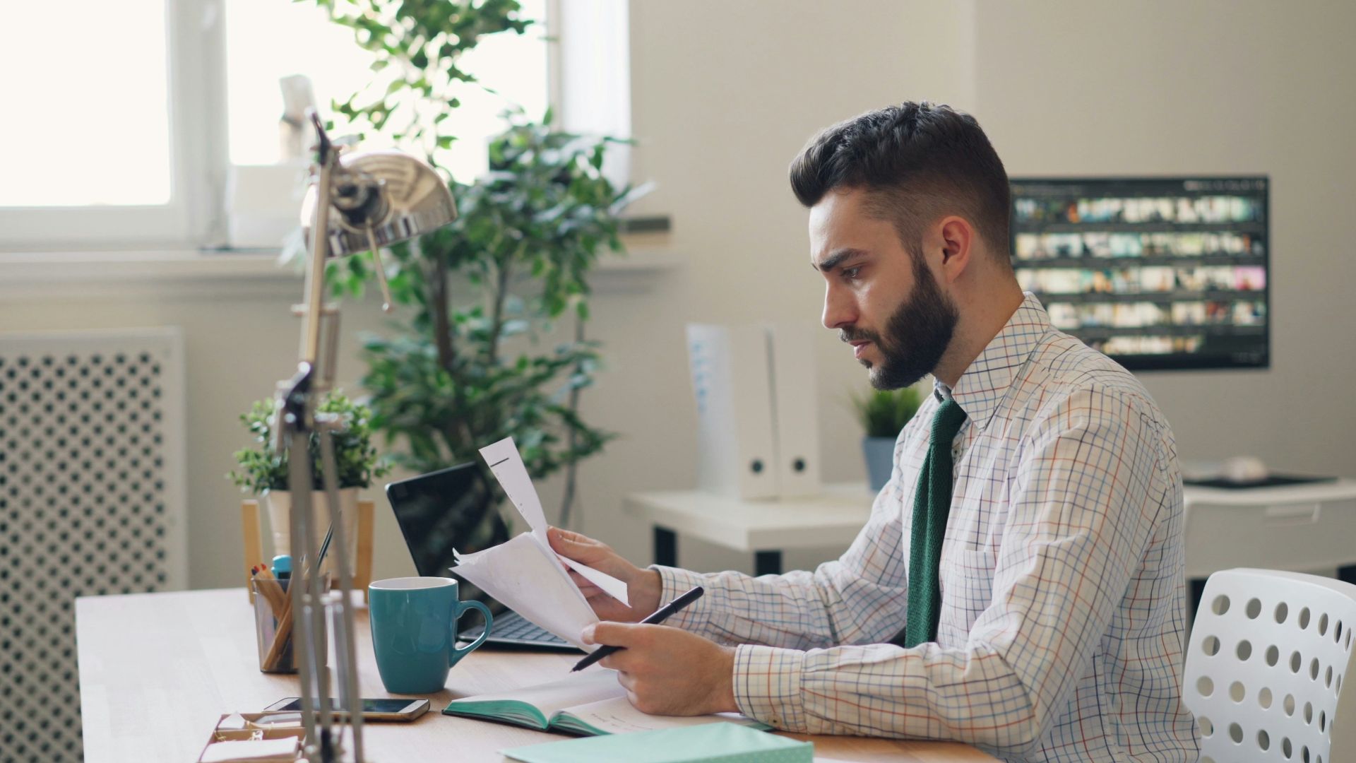 a man sitting at a desk with a laptop and papers