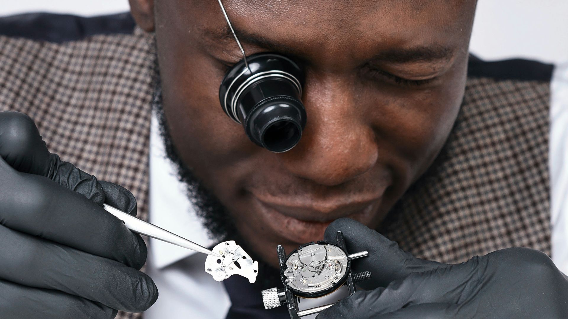 A man in a suit and tie is fixing a watch
