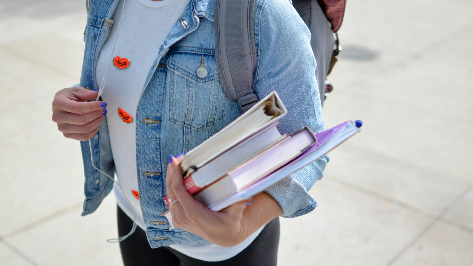 woman wearing blue denim jacket holding book
