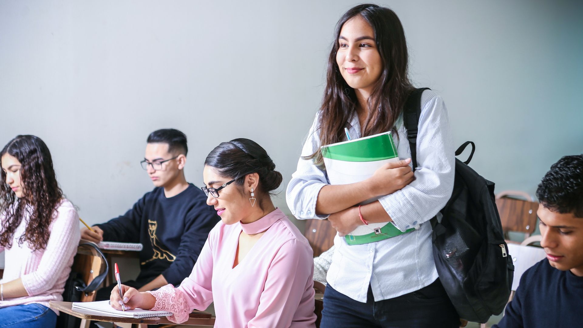 woman carrying white and green textbook