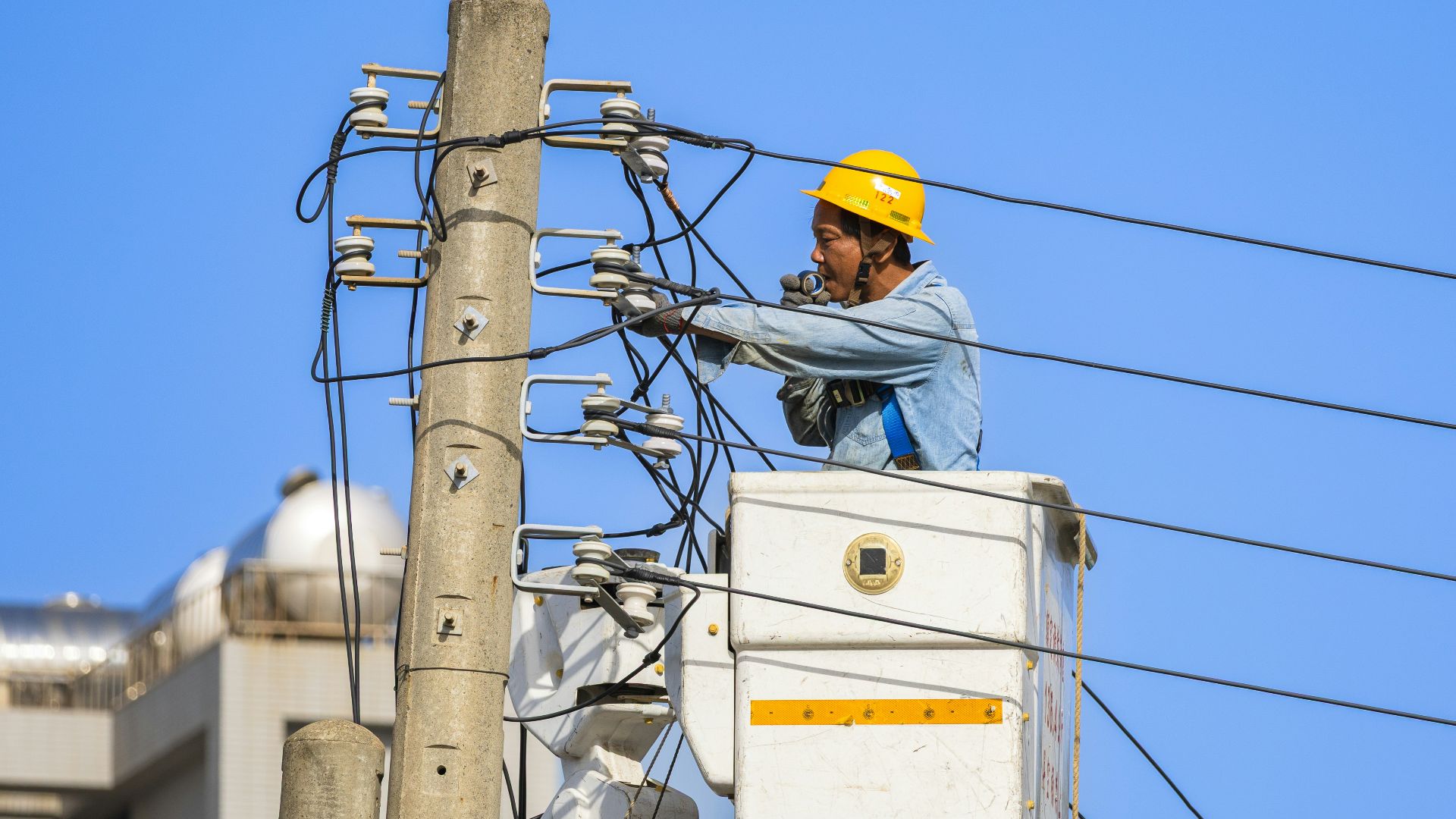 An electrician works on power lines from a lift.