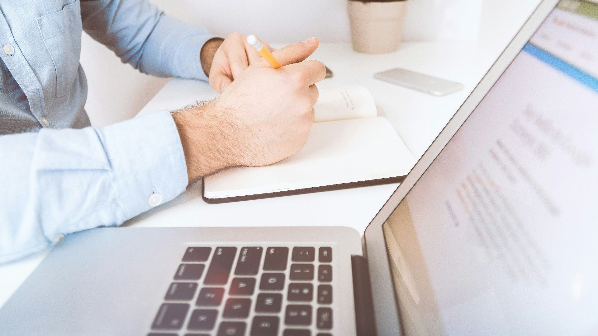 person writing on white notebook
