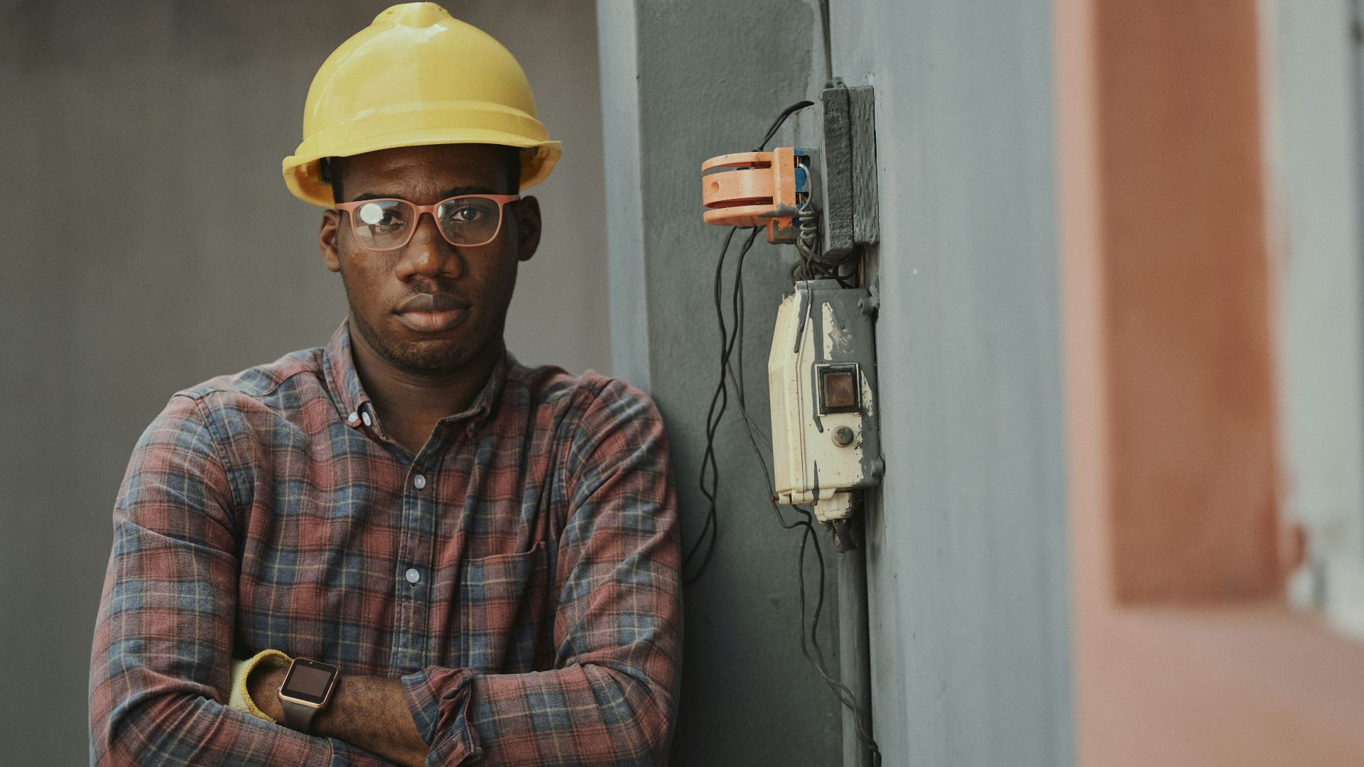 man in blue white and red plaid button up shirt wearing yellow hard hat holding black