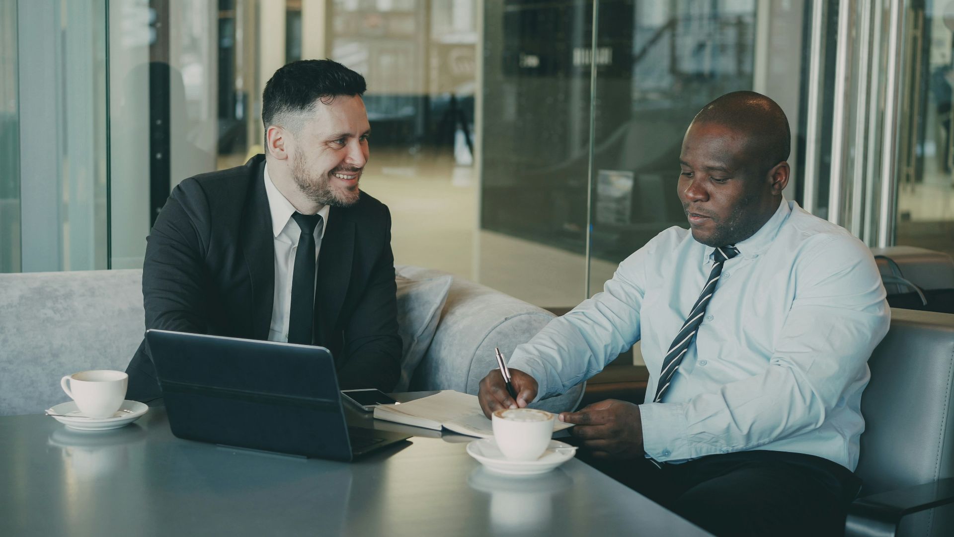 Two businessmen discussing documents over coffee