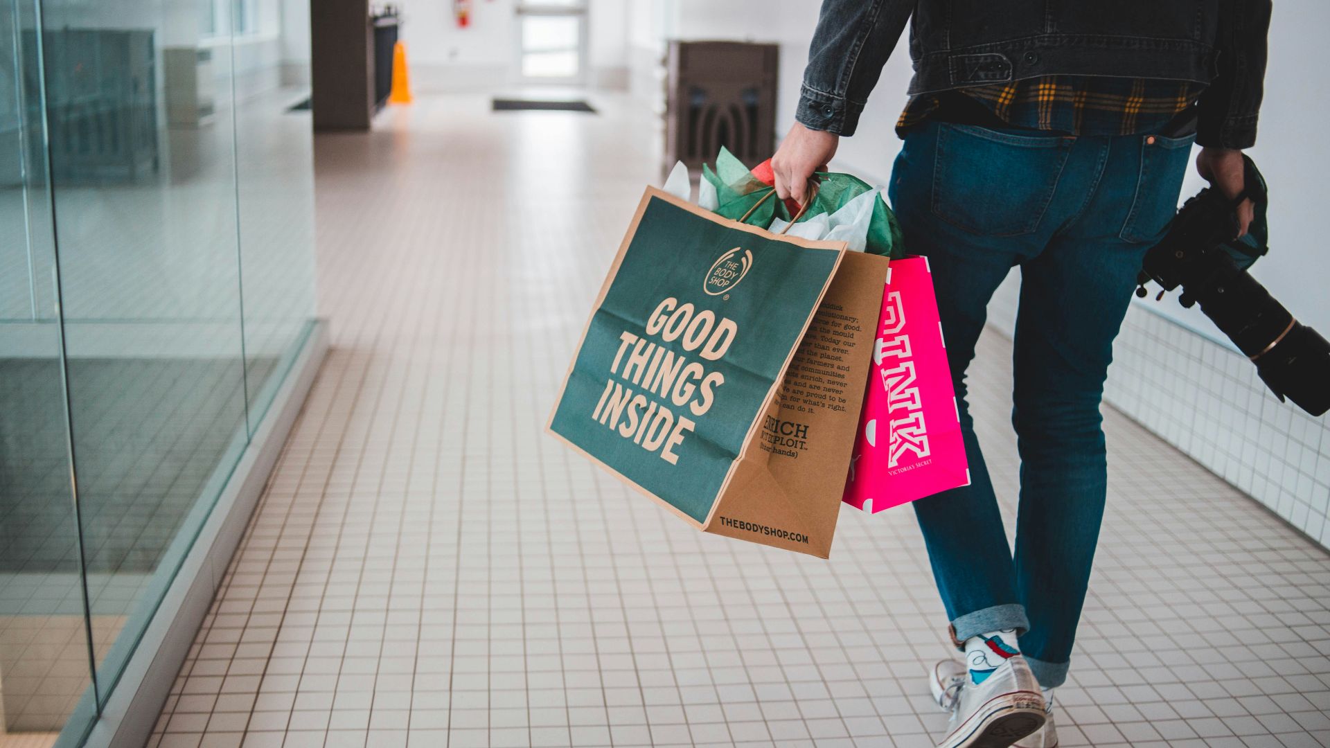 person walking while carrying a camera and paper bags