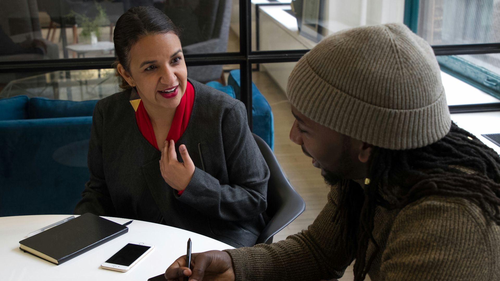 a woman sitting at a table talking to another woman
