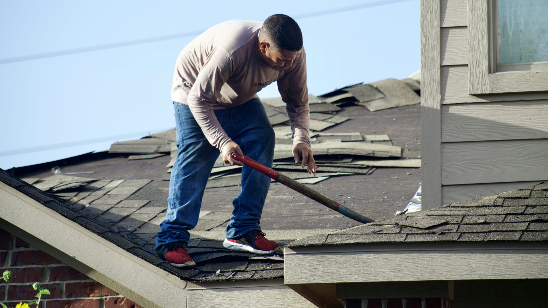 a man with a hammer on top of a roof