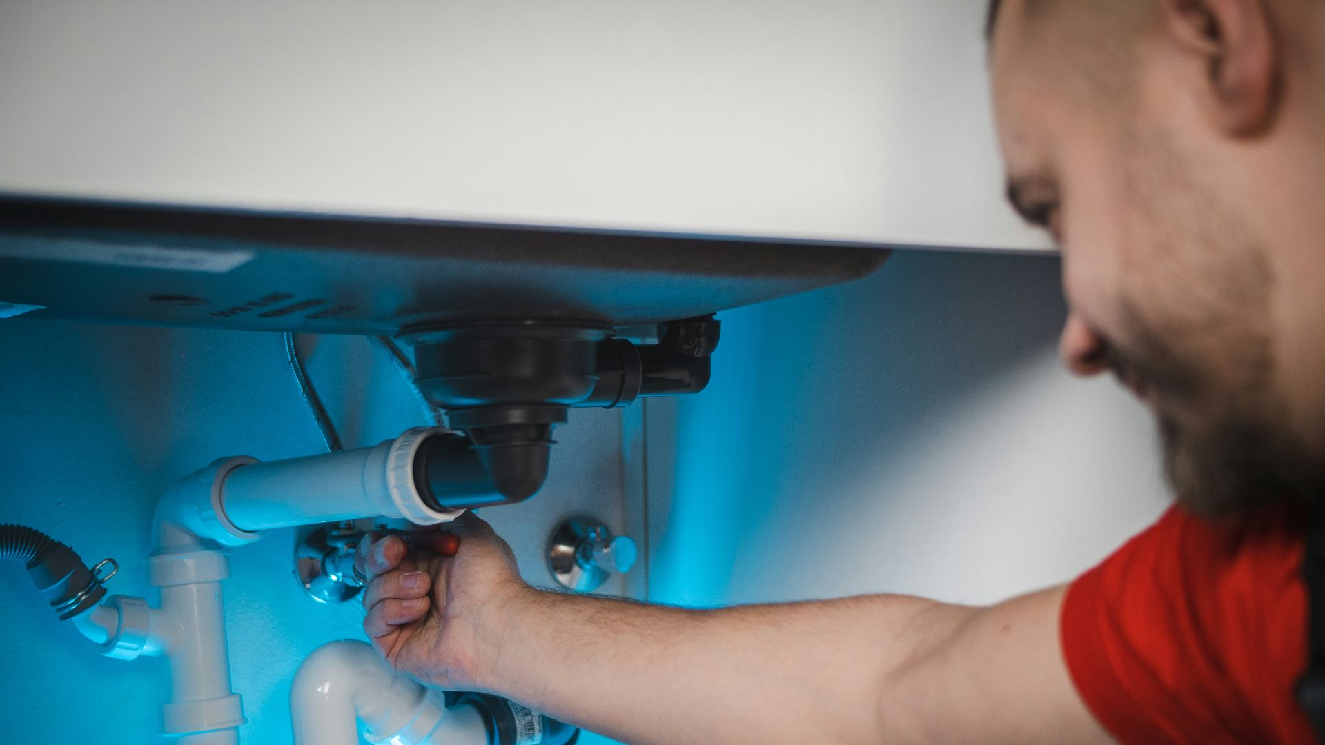 a man working on a pipe in a wall