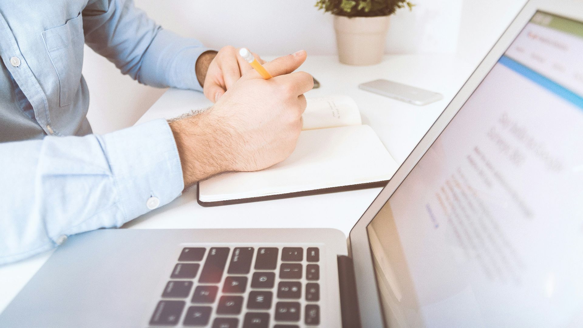 person writing on white notebook