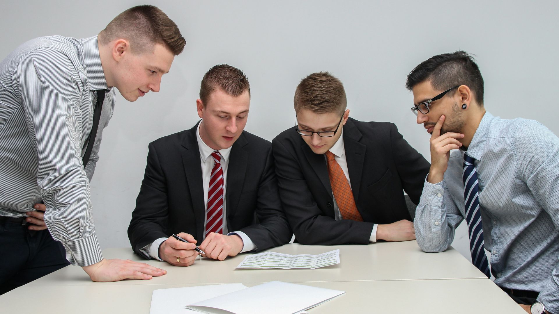 four men looking to the paper on table