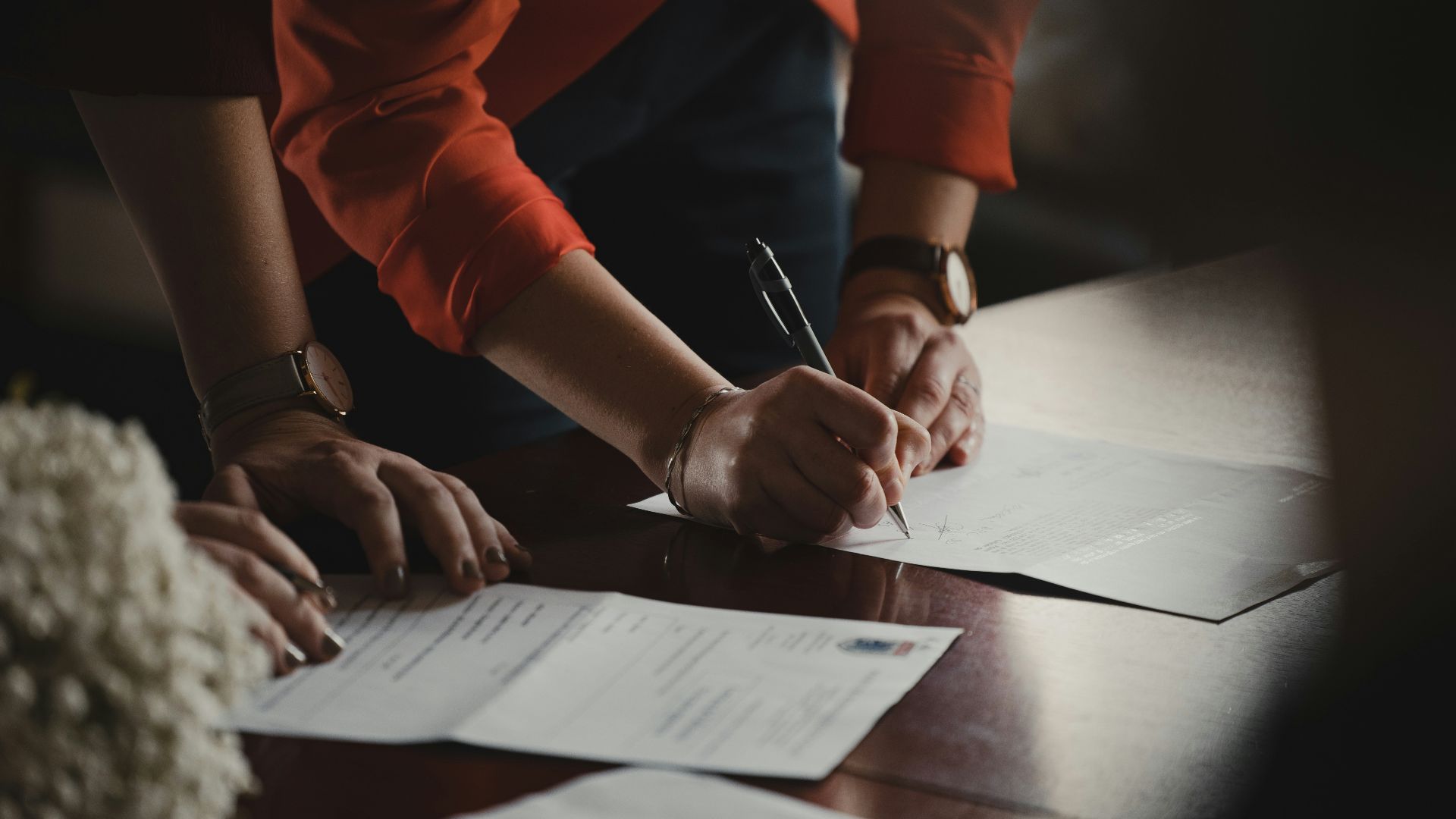 person in orange long sleeve shirt writing on white paper