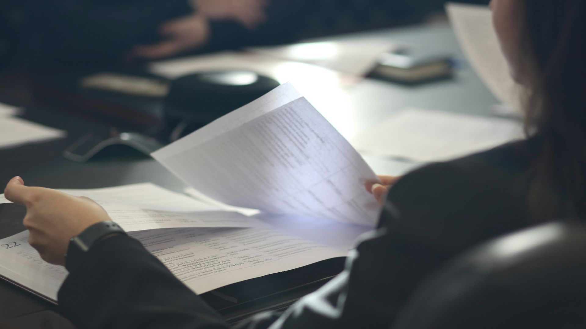 a woman sitting at a table reading a paper