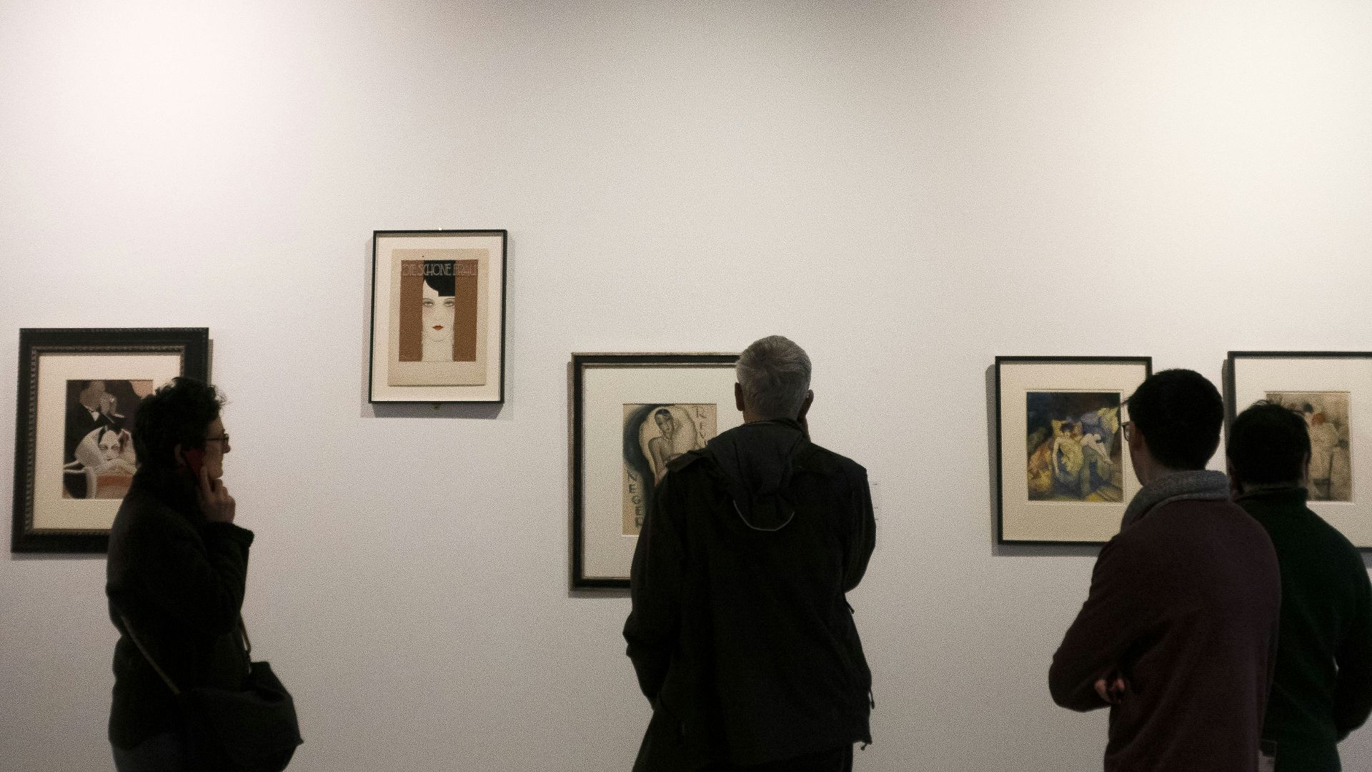 four people watching paintings on wall