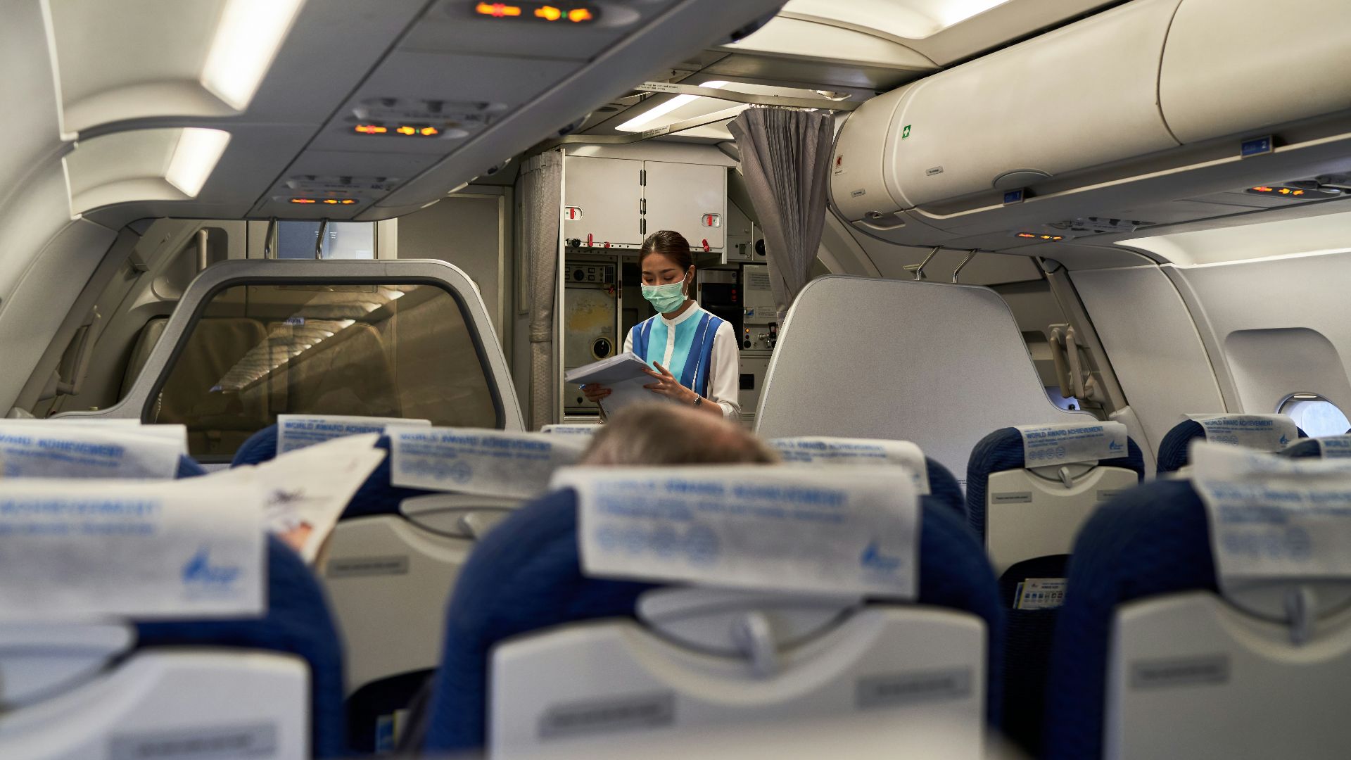 a woman in a face mask sitting on an airplane