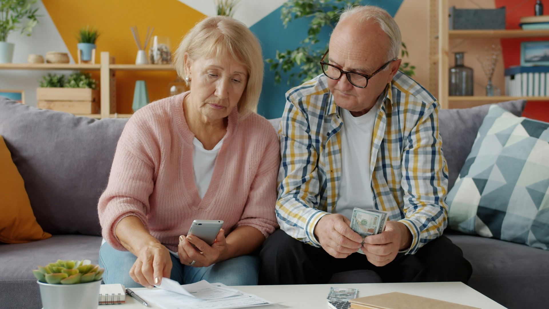 Elderly couple looking at bills and phone