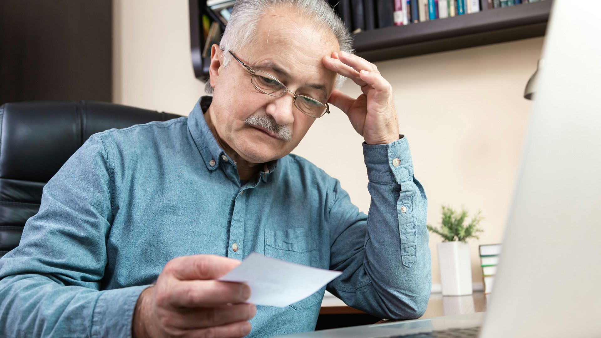 a man holding a pen and looking at a laptop