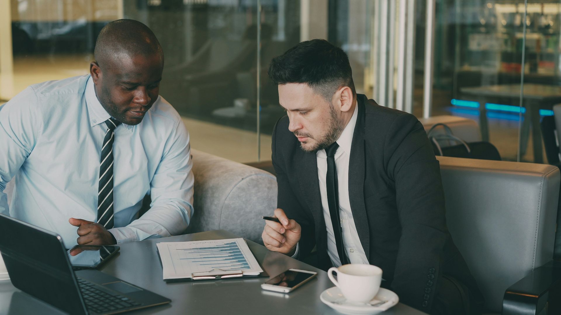 Two businessmen reviewing documents at a table.