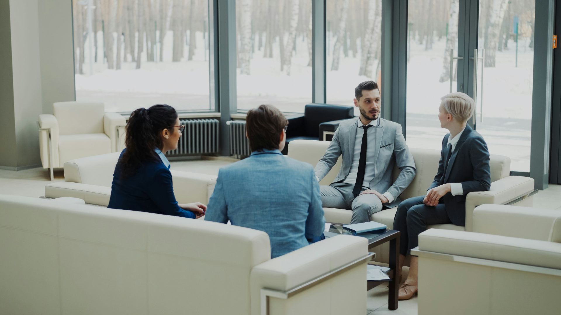 Four professionals in a modern office meeting space.