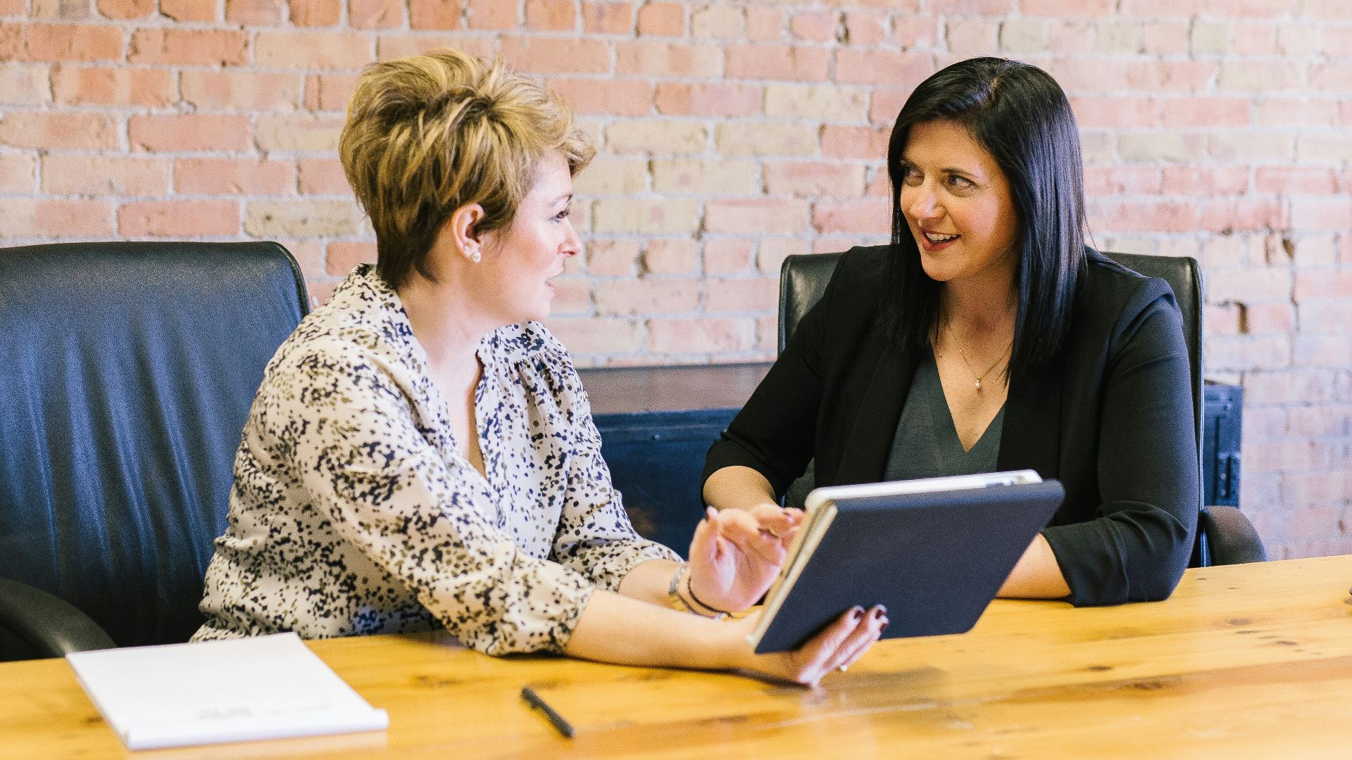 two women sitting on leather chairs in front of table