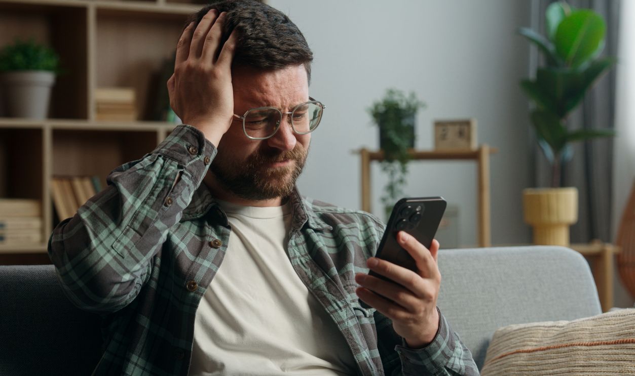 Caucasian man male guy supporter gamer playing video game smartphone at home worried looking at mobile phone online bet gambling sport match betting casino waiting sad disappointed lost failure looser