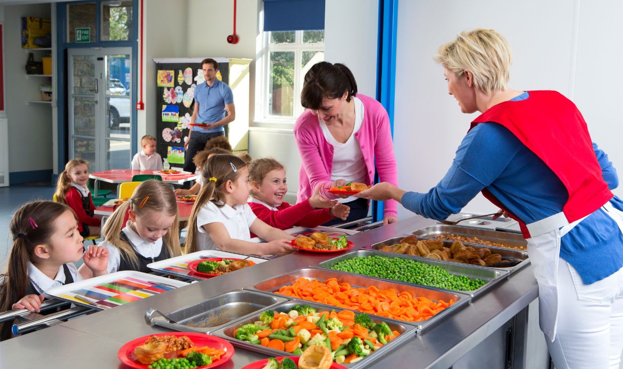Dinner is served to children as they line up at a school canteen