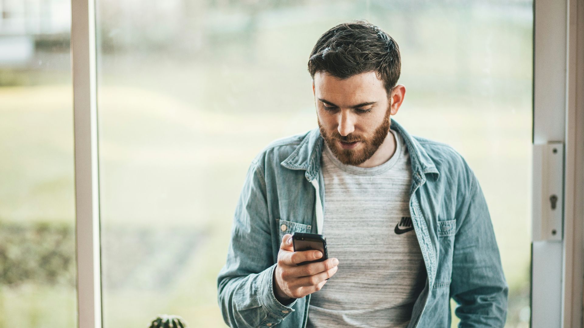 man holding a smartphone near the window