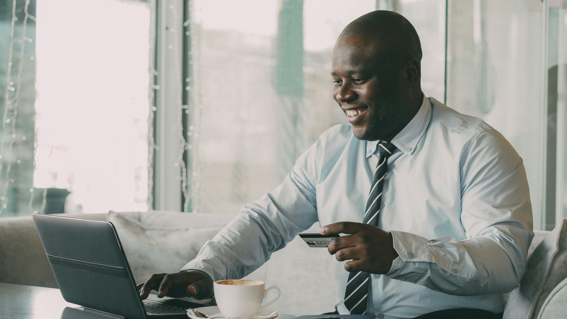 Man with credit card using laptop with coffee.