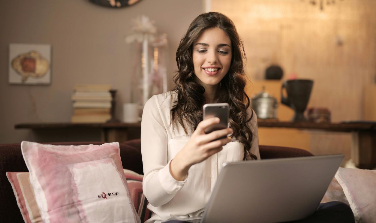 Woman Sitting on Sofa While Looking at Phone