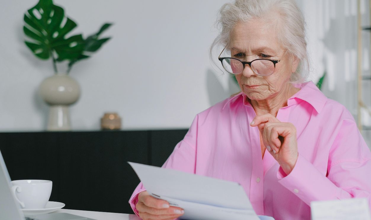 An Elderly Woman in Pink Long Sleeves Looking at Documents