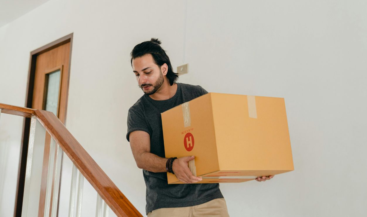 An adult man carrying a box