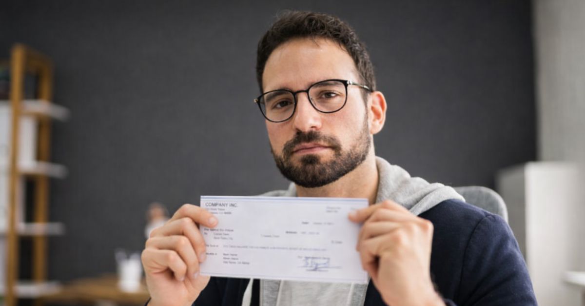 1854581986 - Andrey_Popov - Holding Paycheck Or Payroll Check Or Insurance Cheque In Hand
