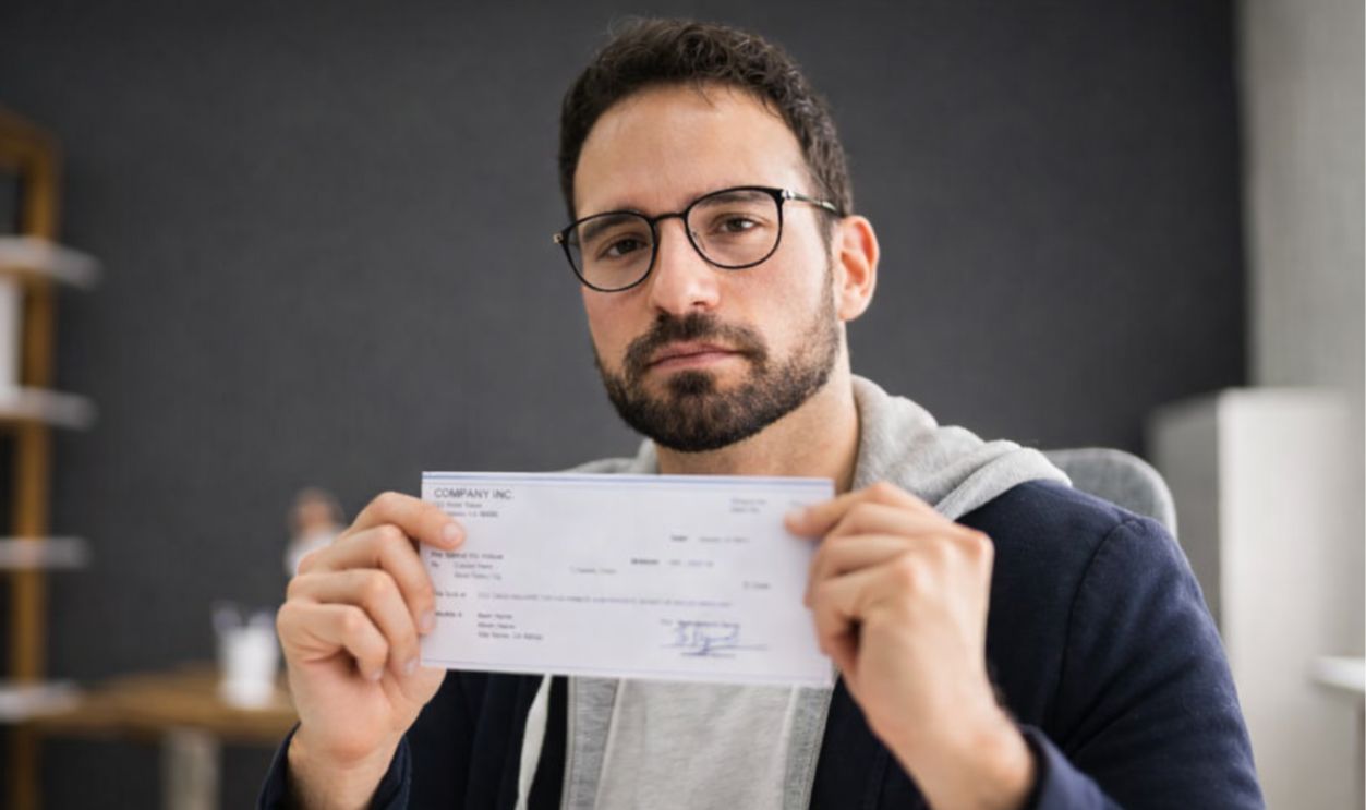 1854581986 - Andrey_Popov - Holding Paycheck Or Payroll Check Or Insurance Cheque In Hand