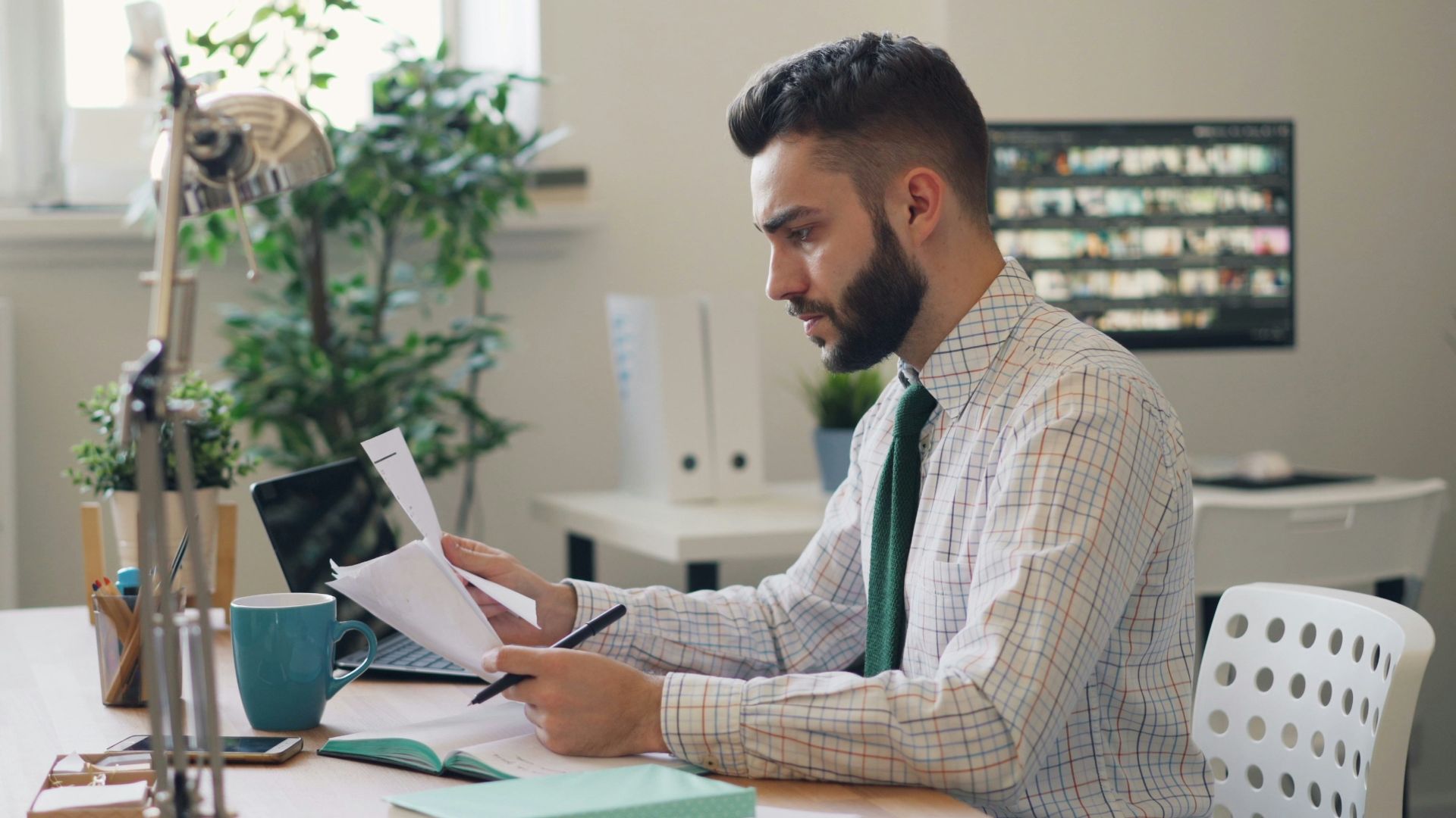 a man sitting at a desk with a laptop and papers