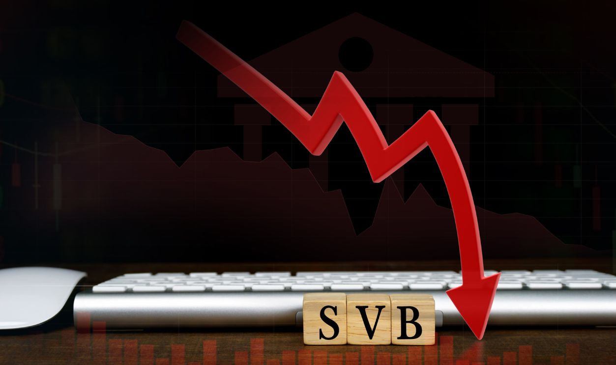 SVB (Silicon Valley Bank) with keyboard and mouse, stock market chart, and red arrow pointing down. biggest bank in Silicon Valley, stocks fall.                      