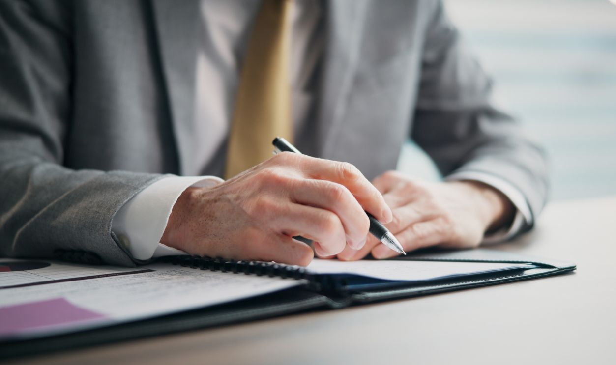 Business person, hands and writing with documents for corporate finance, proposal or budget planning at office. Japan, closeup or financial planner with paperwork or pen for company report or policy