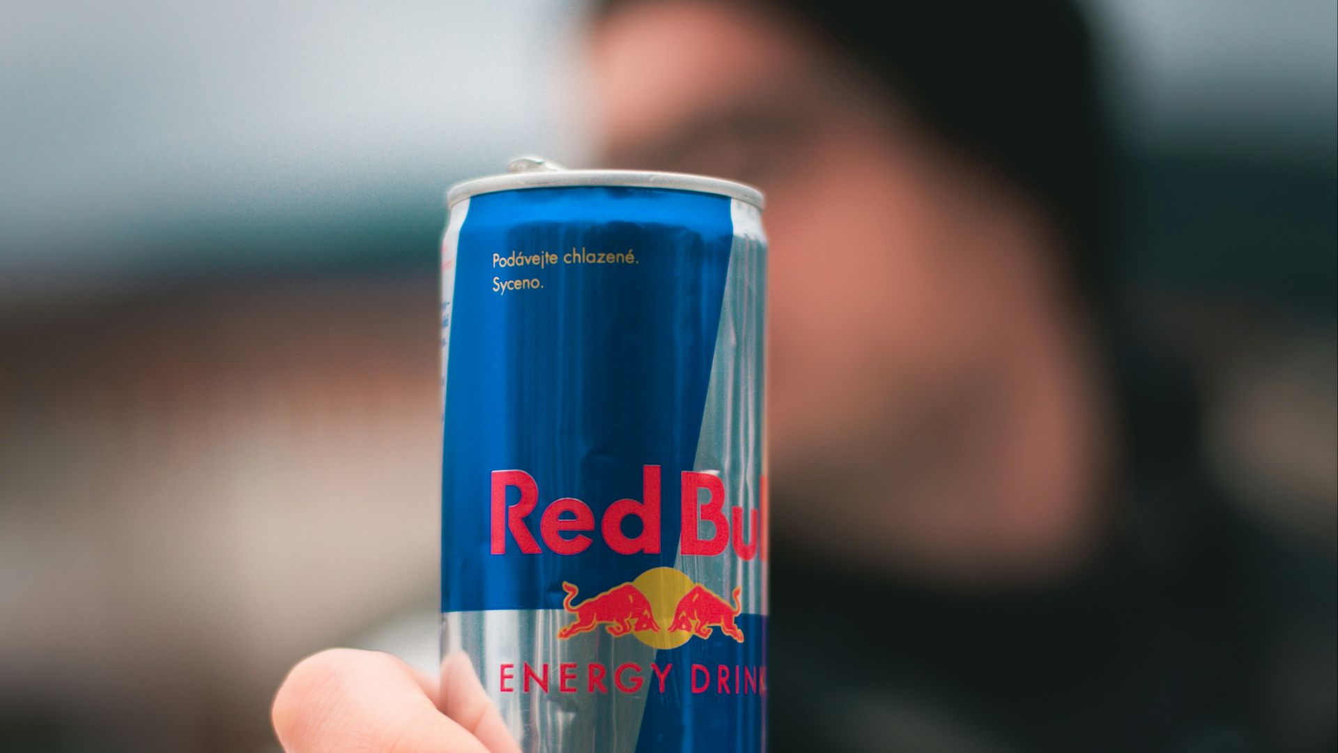 person holding red bull energy drink can