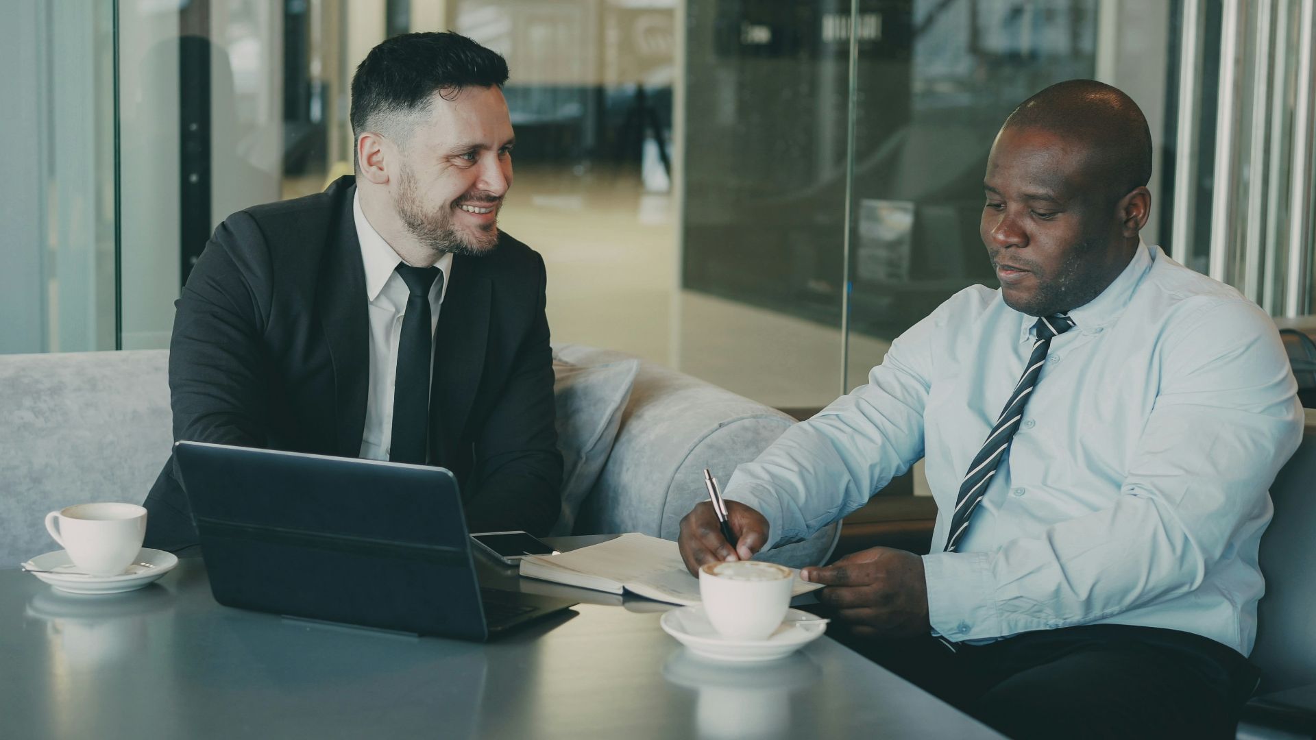 Two businessmen discussing documents over coffee