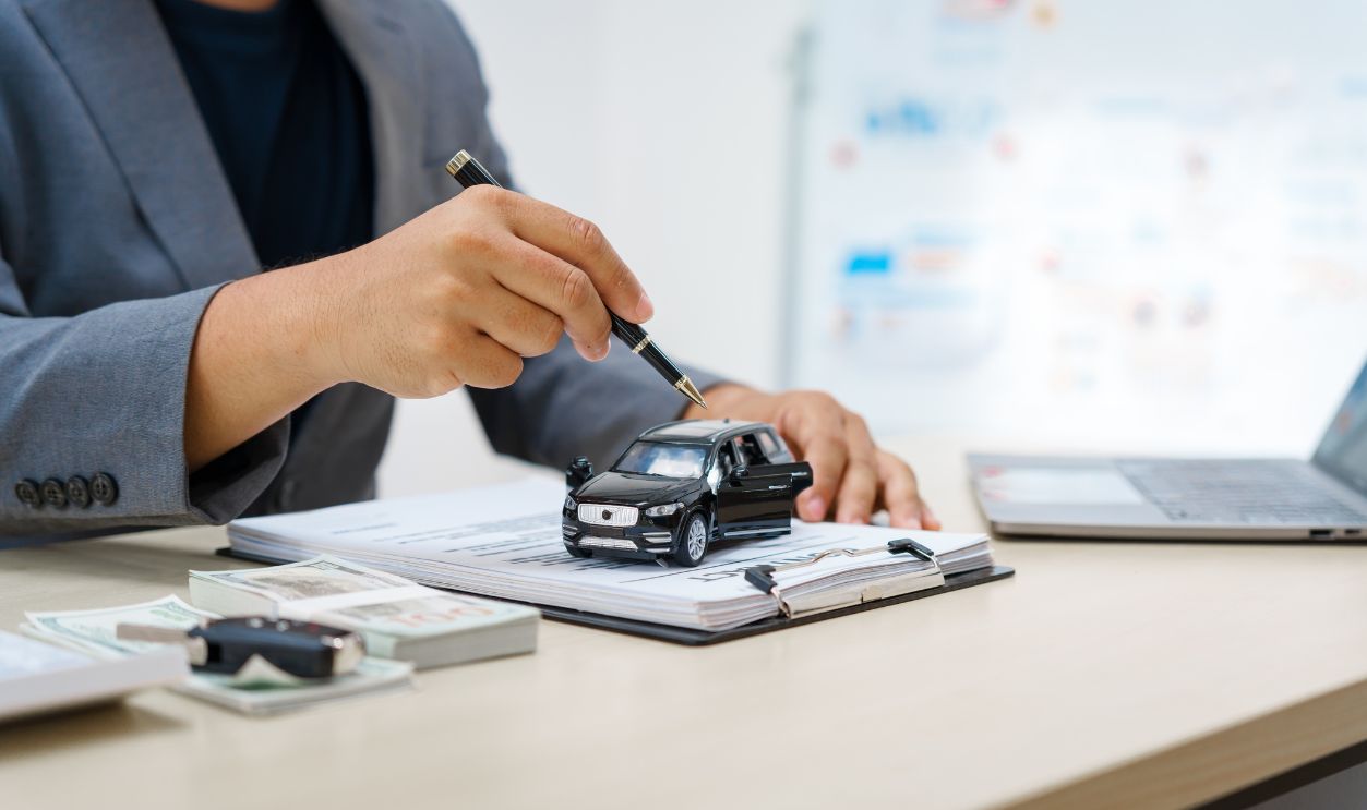 Asian business professional in a formal suit works at a desk, reviewing financial charts. manage car insurance claims, analyze auto loan options, sign lease agreements for vehicle transactions.