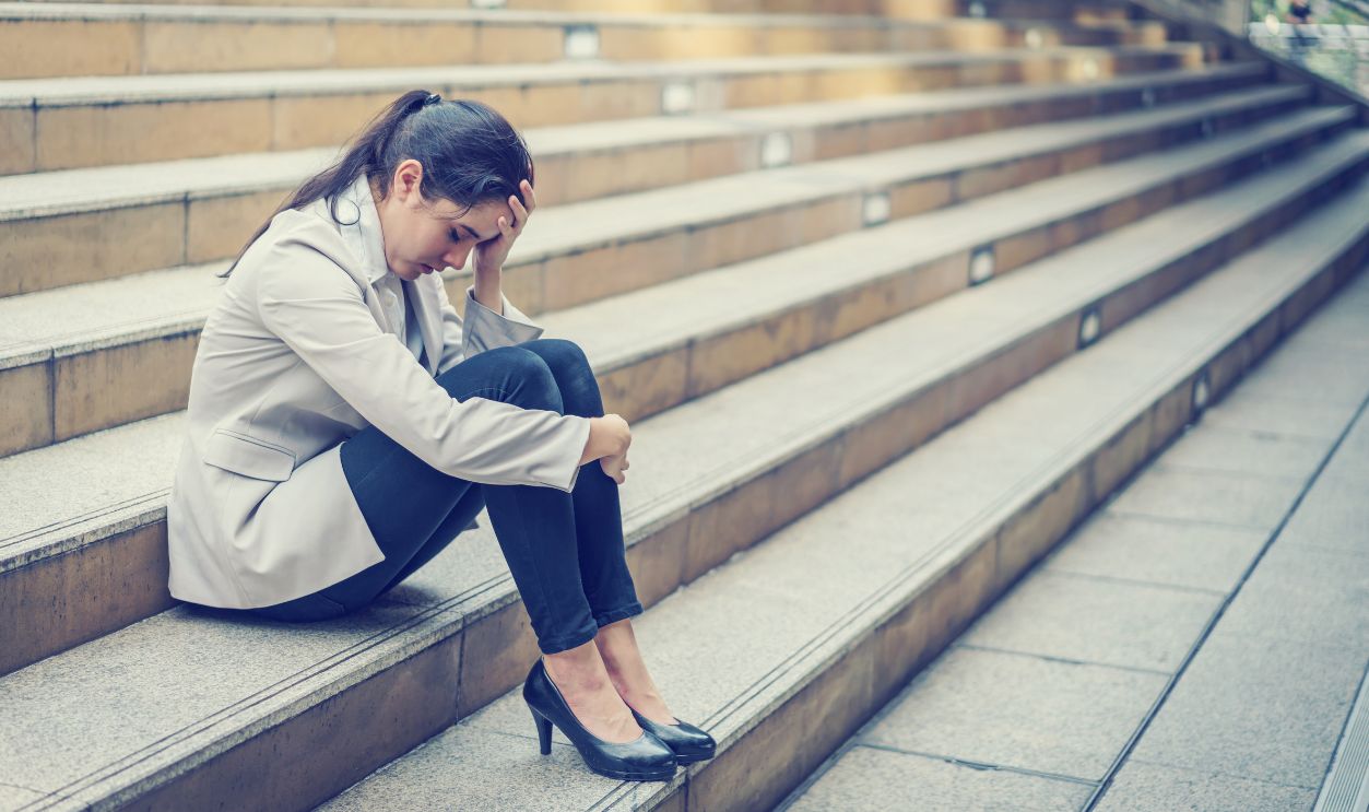 Business woman stressed from work while sitting outdoors on the stairs, concept work life balance, burn out syndrome, press from colleagues.
